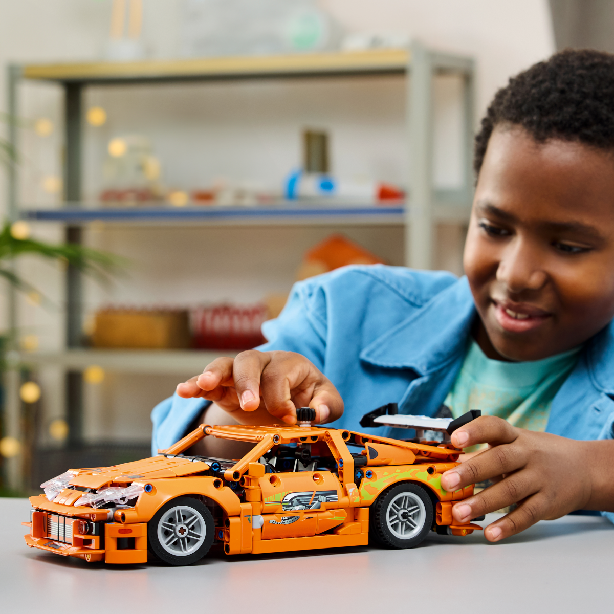 Child playing with LEGO Technic Fast and Furious Toyota Supra MK4 set, on a table.