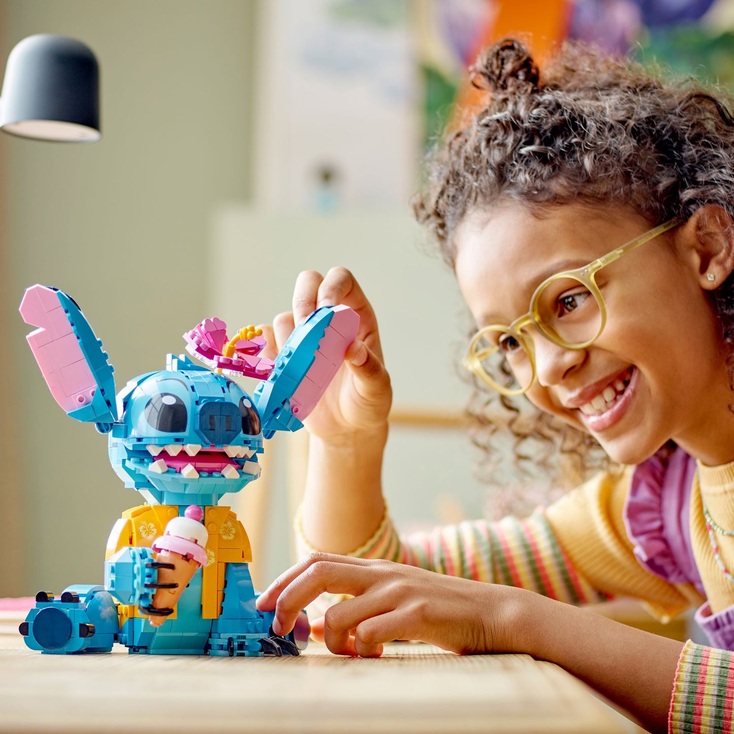 Child playing with LEGO Disney set featuring the character Stitch with a Hawaiian shirt and an ice cream cone.