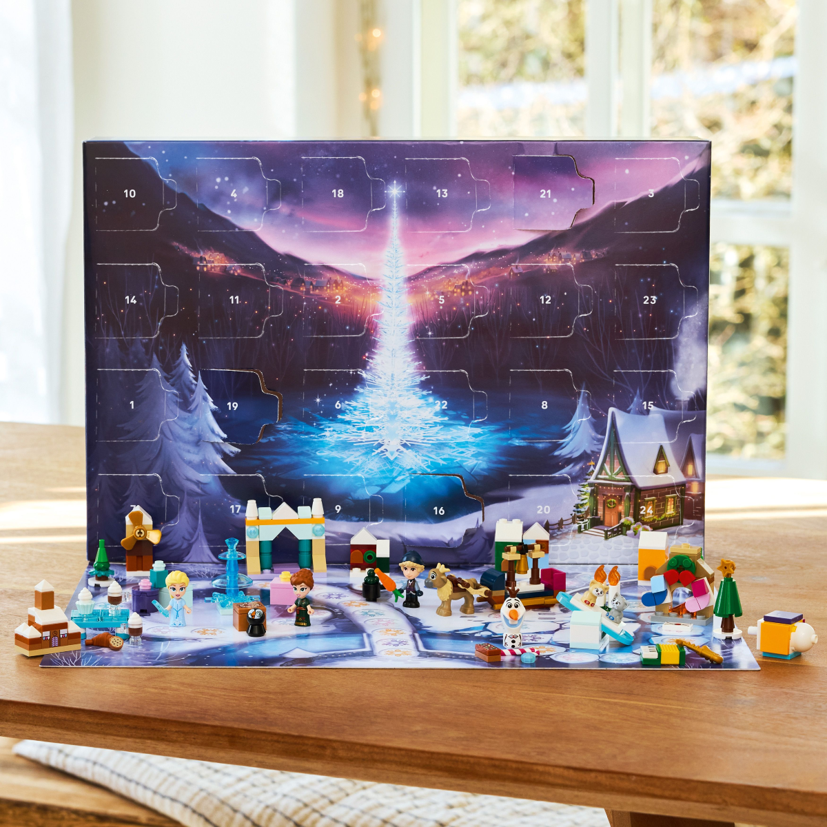 LEGO Disney Frozen advent calendar and all 24 gifts figures from it, on a wooden table.