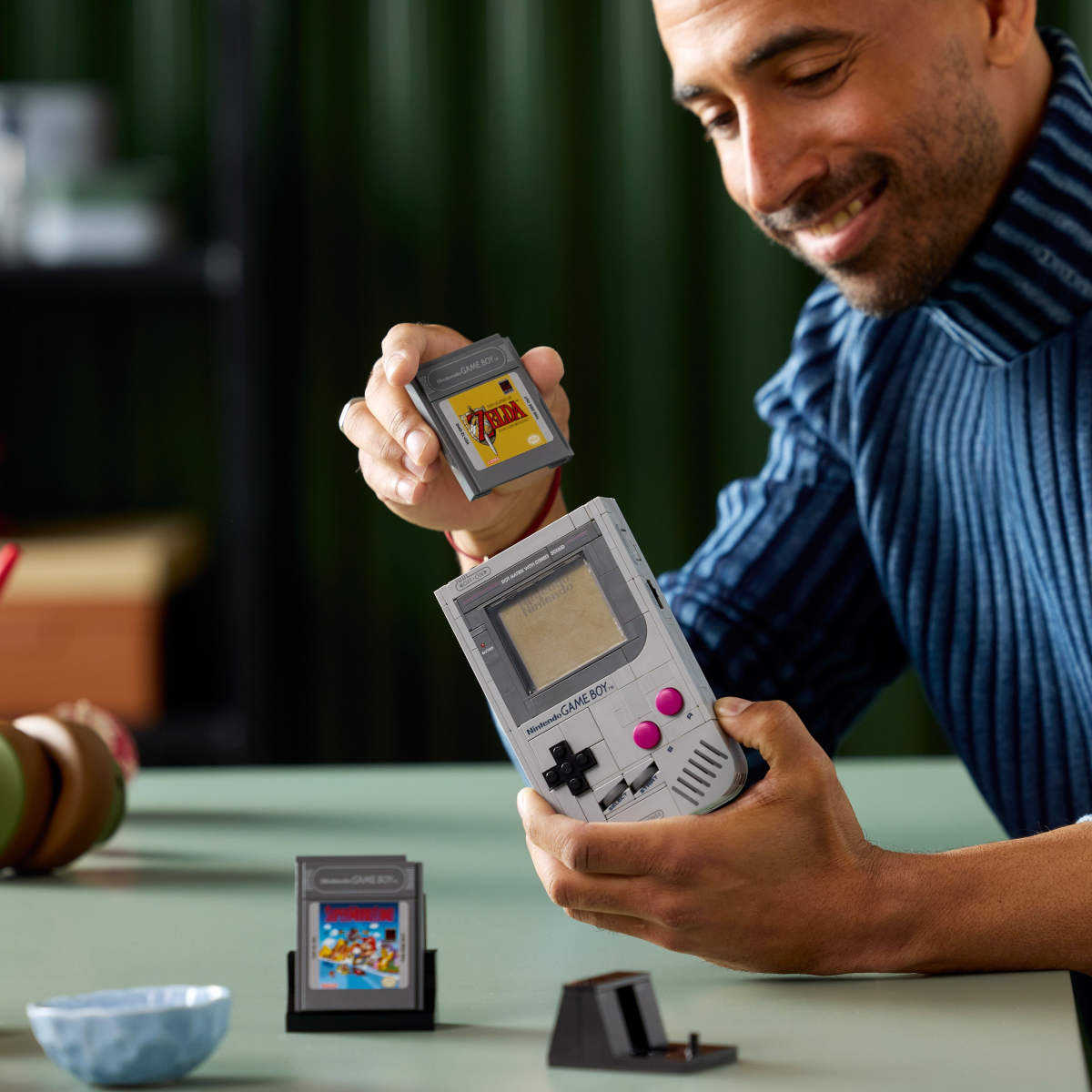 Man holding a LEGO Game Boy console with games in front of him