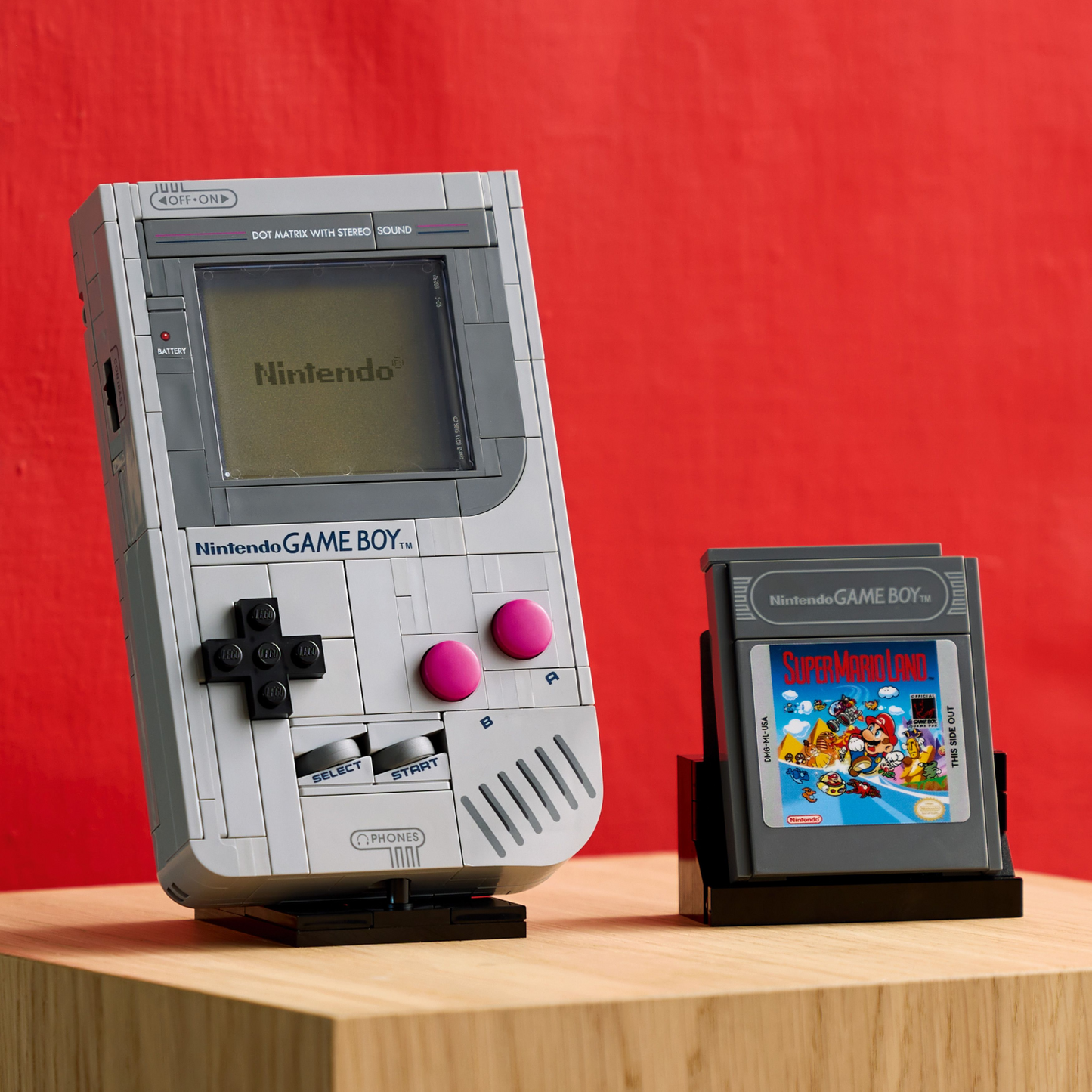 LEGO Nintendo Game Boy models on a wooden surface with a red background