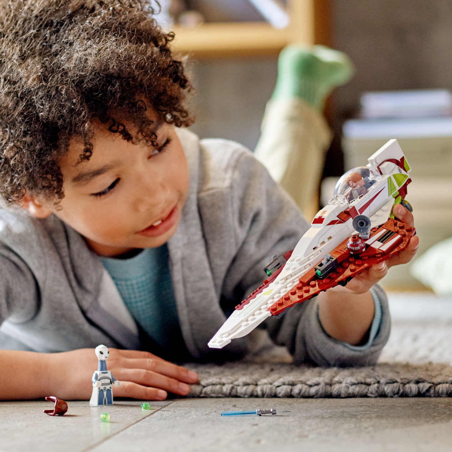 Child playing with a toy spaceship on a carpeted floor.