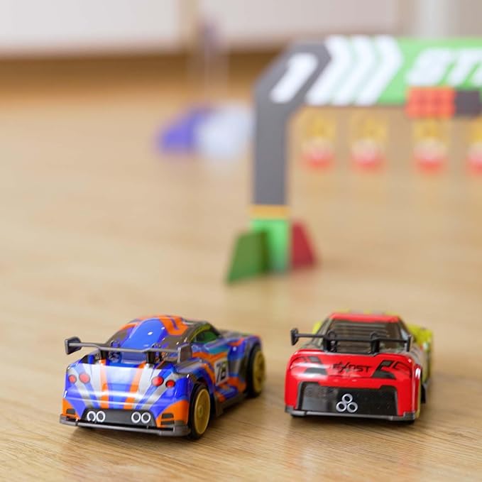 Two toy cars on a wooden surface with a blurred track in the background