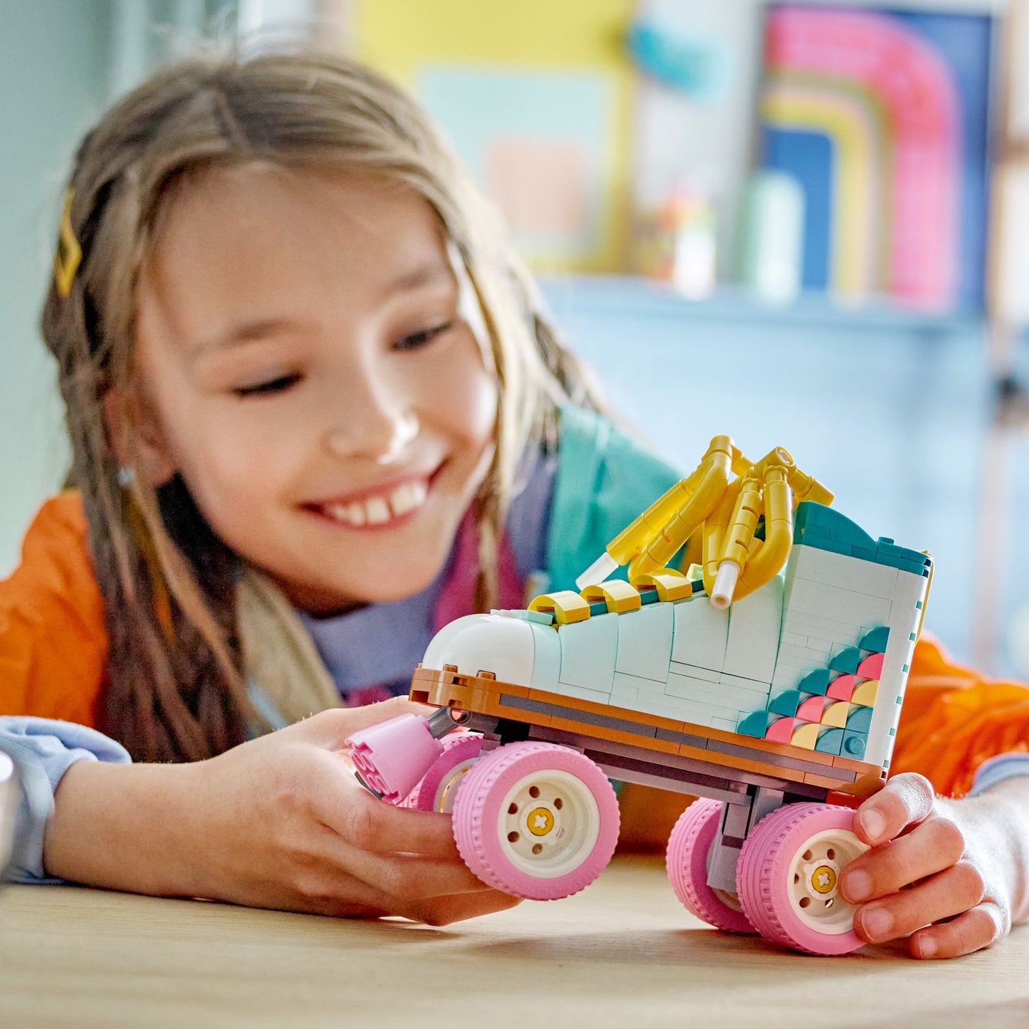 Child holding a colorful toy LEGO roller skate in a bright room