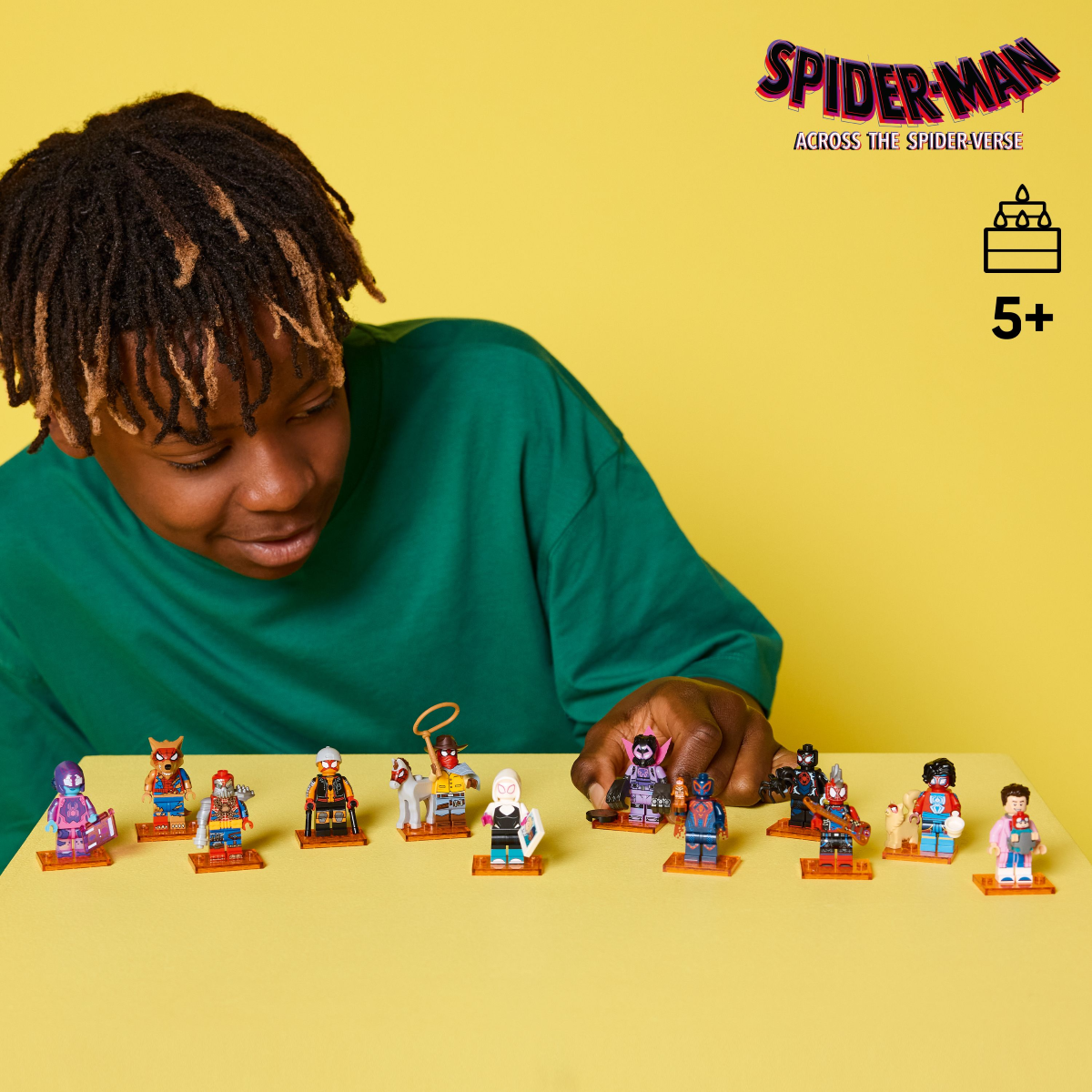 Child playing with LEGO Spider-Man  minifigures on a yellow background, with 'Spider-Man: Across the Spider-Verse' branding.