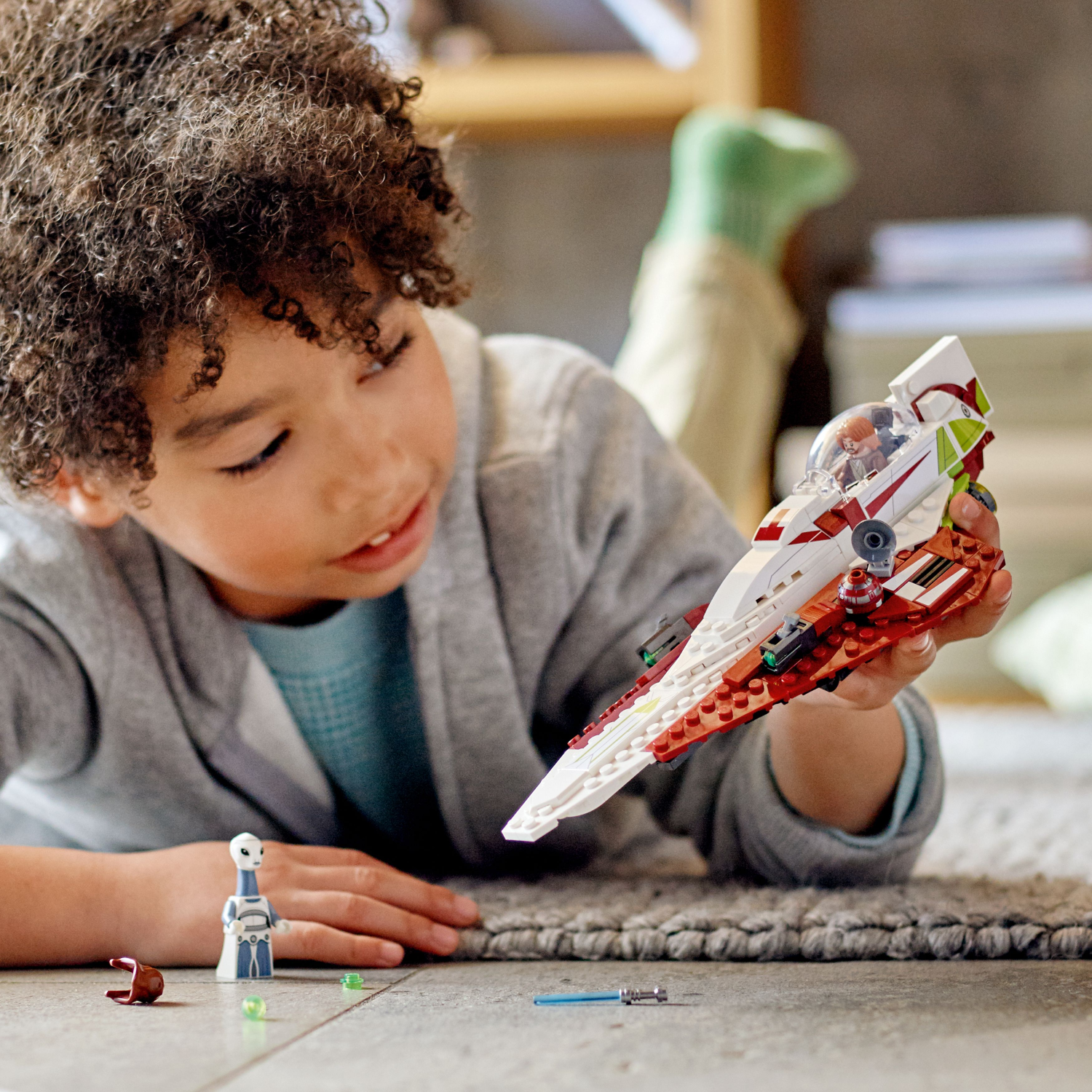 Child playing with a toy spaceship on a carpeted floor.