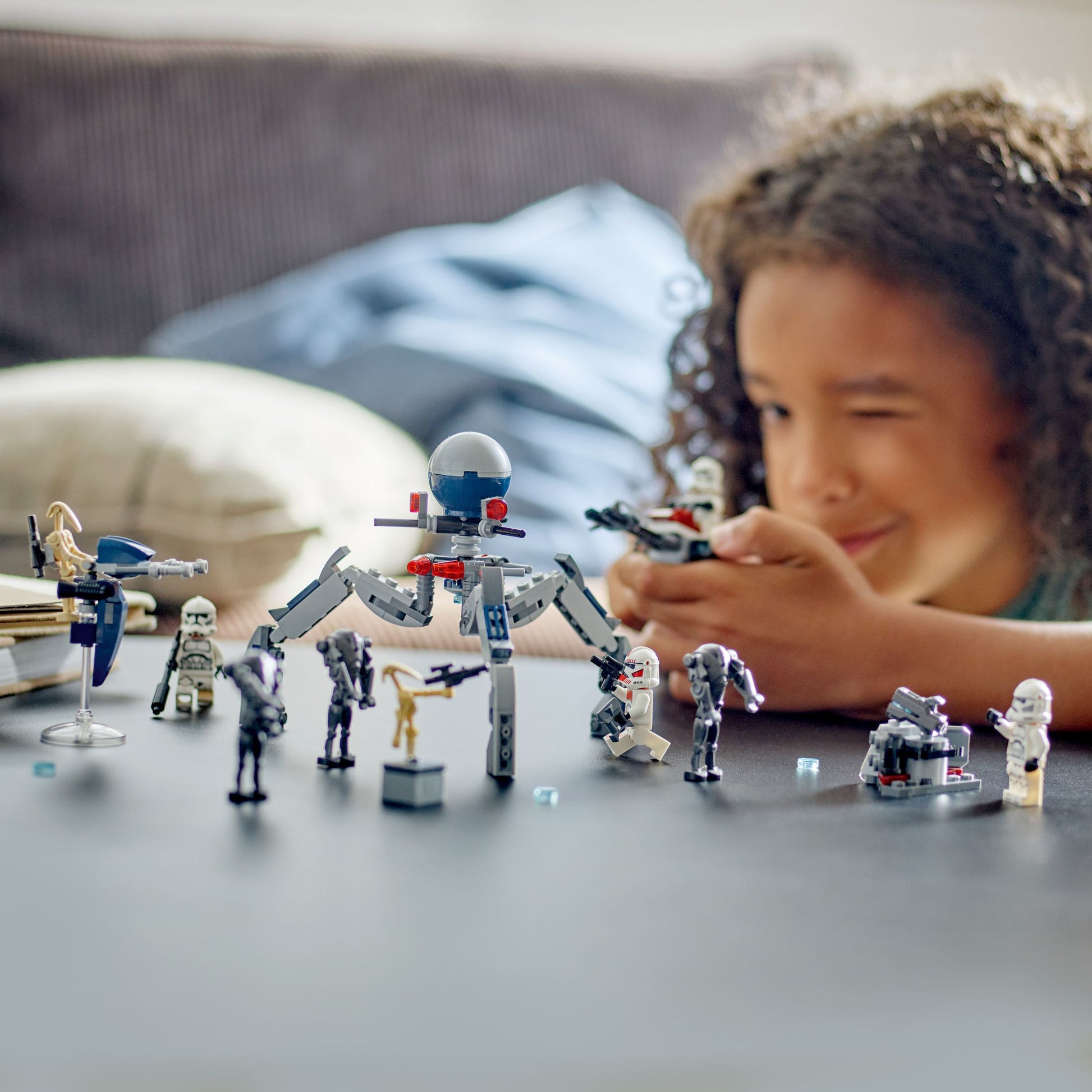Child playing with toy figures on a table, with a focus on the toys.