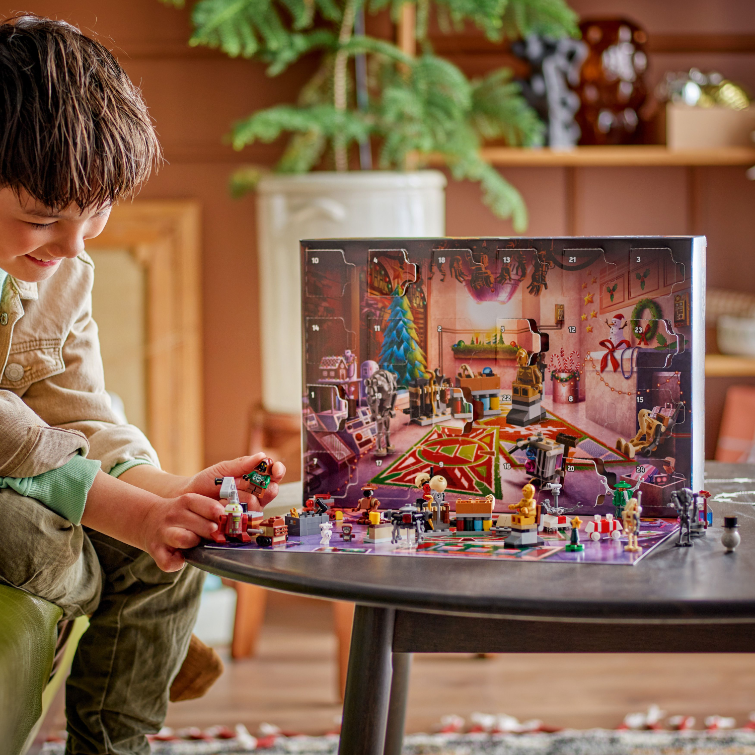 Child playing with LEGO Star Wars Advent Calendar and all the gifts, on a table.