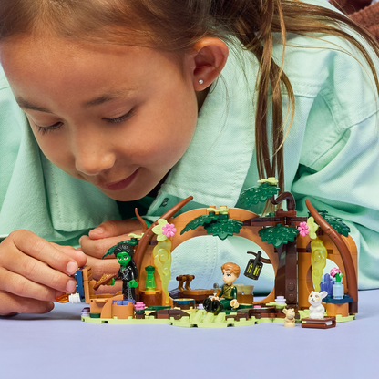child playing with LEGO Wicked Elphaba's Retreat set with characters and a fantasy scene including a wooden arch and plants.