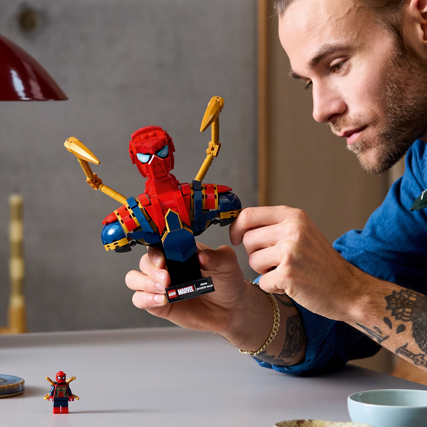 Man holding LEGO Iron Spiderman Bust, with a spiderman minifigure on the table.