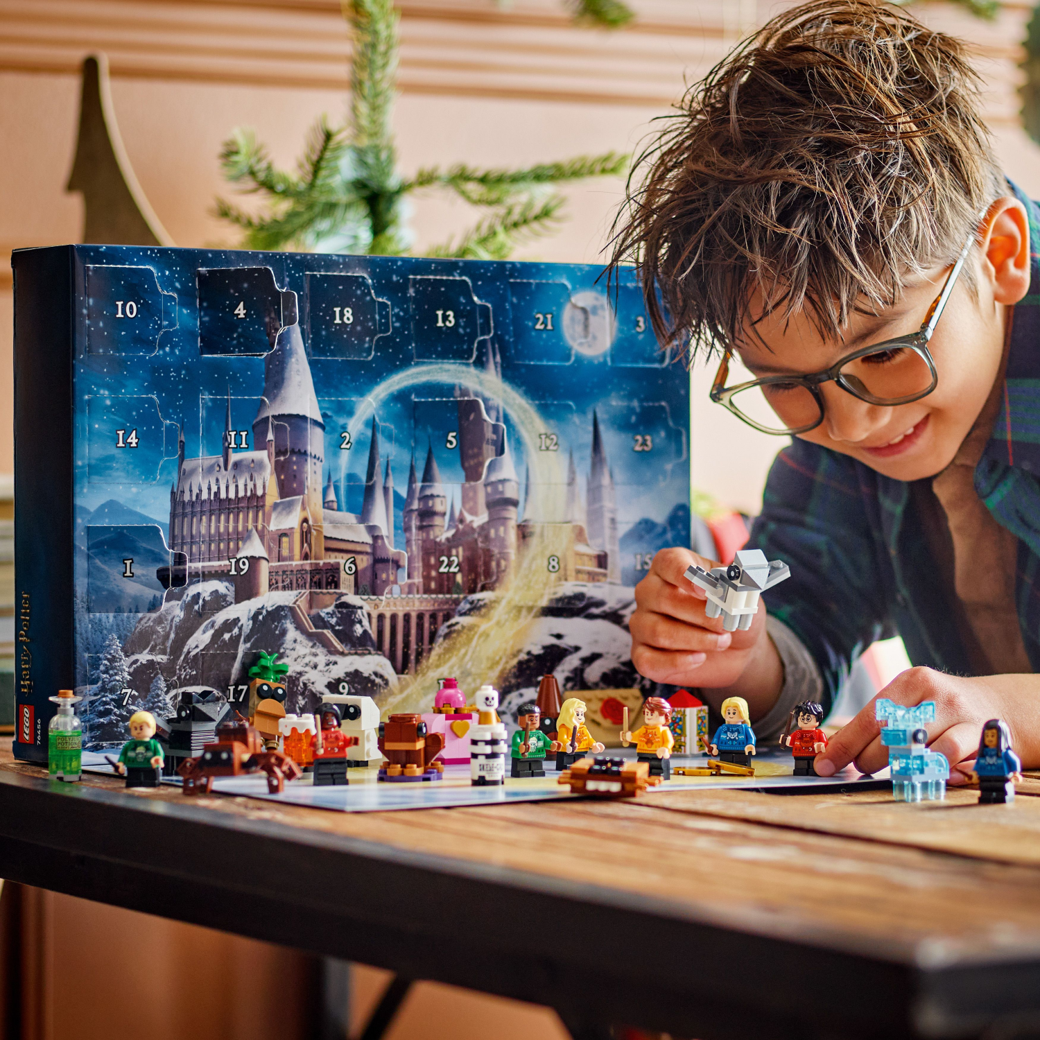 Child playing with LEGO Harry Potter Advent Calendar, with all 24 gifts, on a wooden table.