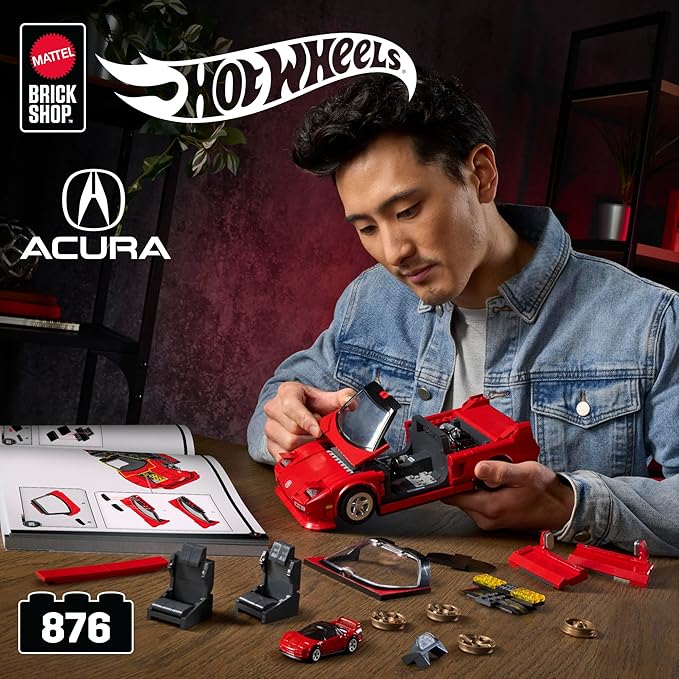 Person assembling a Hot Wheels Acura toy car set with branding visible.